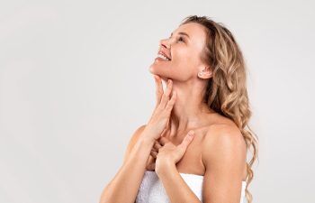 Happy mature woman touching skin on her neck and chin